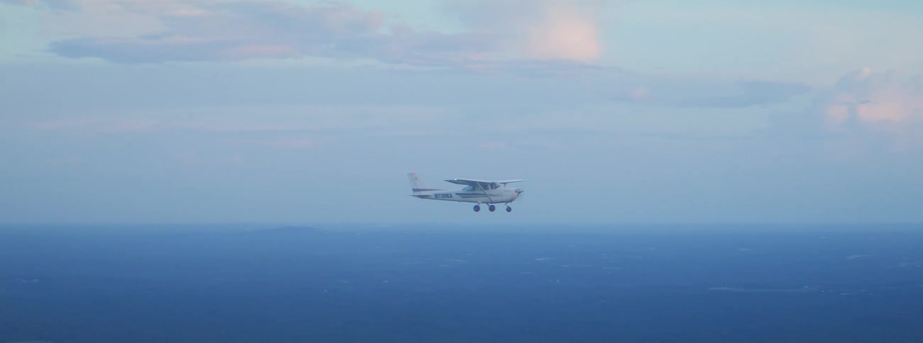 A small plane flying outdoors on a sunny day