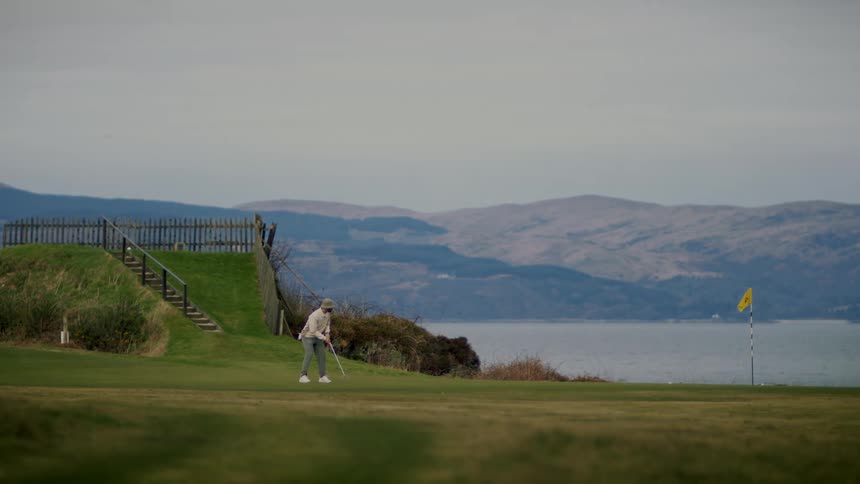 Man playing golf on a golf course next to a lake