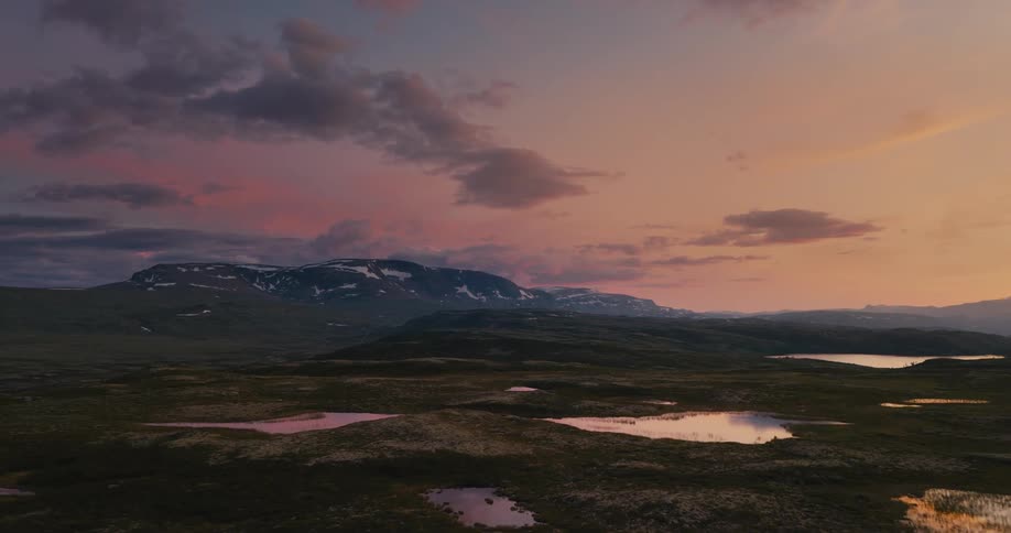 Aerial of pasture with snow melting during sunset