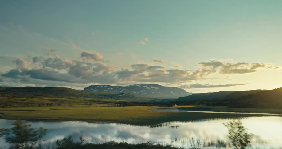 A serene scene of a lake with mountains in the distance at sunset