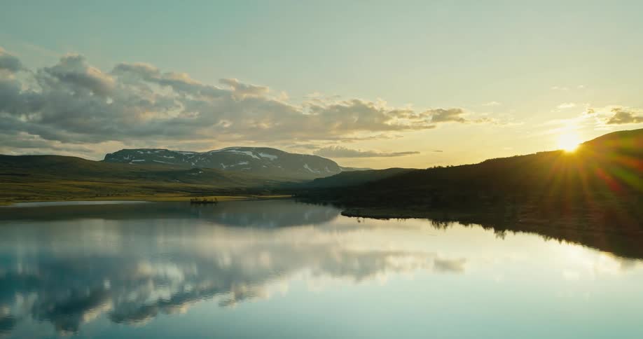 A serene scene of a lake with mountains in the distance at sunset