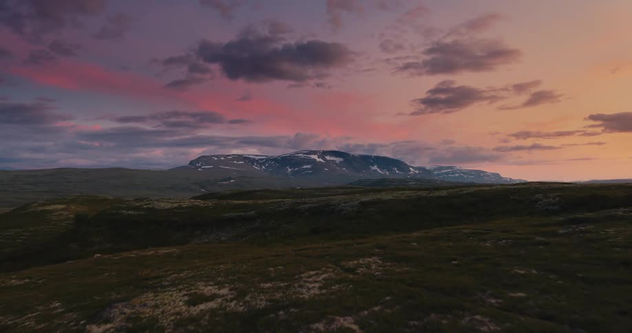Aerial of grassland on hill during sunset