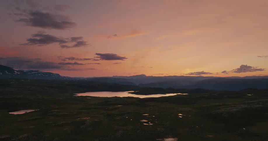 An aerial view of some plains with a sunset in the distance