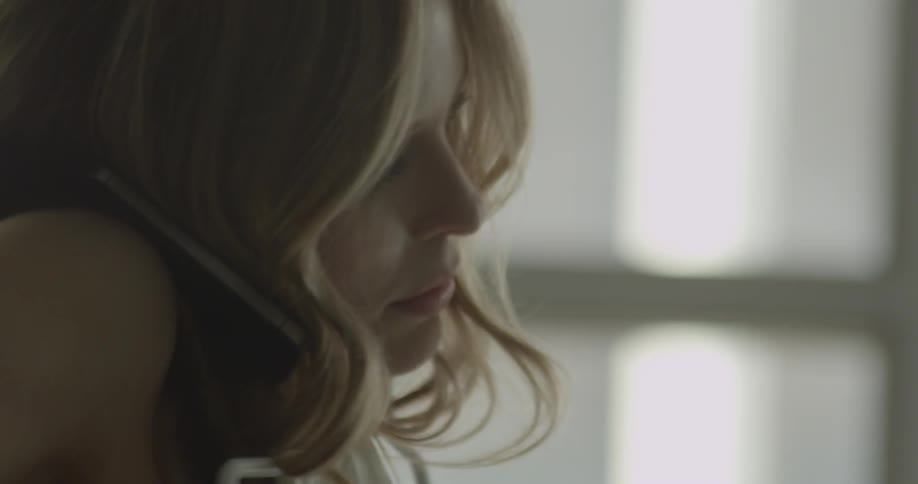 A woman talks on the phone while holding a hanger with clothes against her chest