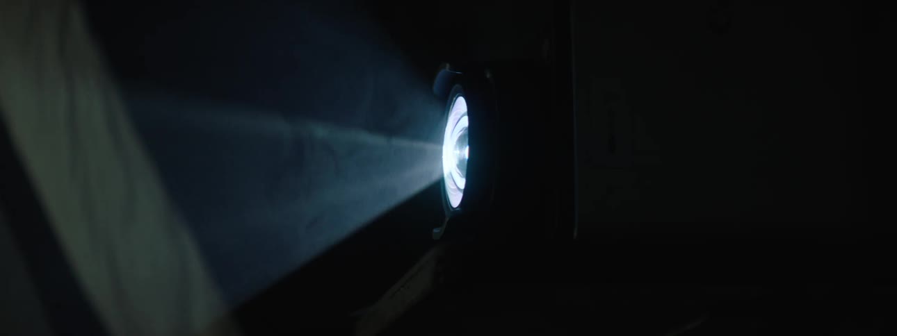 Close up of the lens of a projector on a dark room