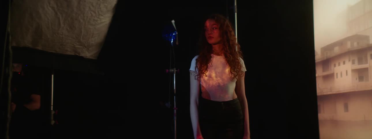 A lady getting a photoshoot in a dark room with a blinking screen