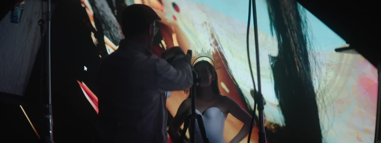Photographer takes pictures of a model in front of a large projector in the background