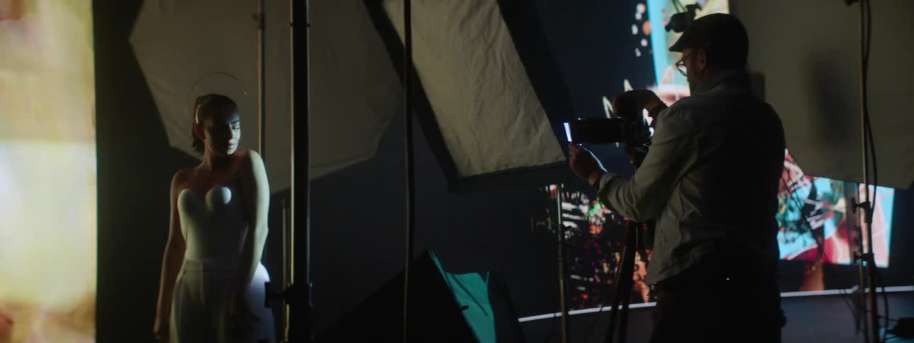 Photographer takes pictures of a model on a stage with a large screen