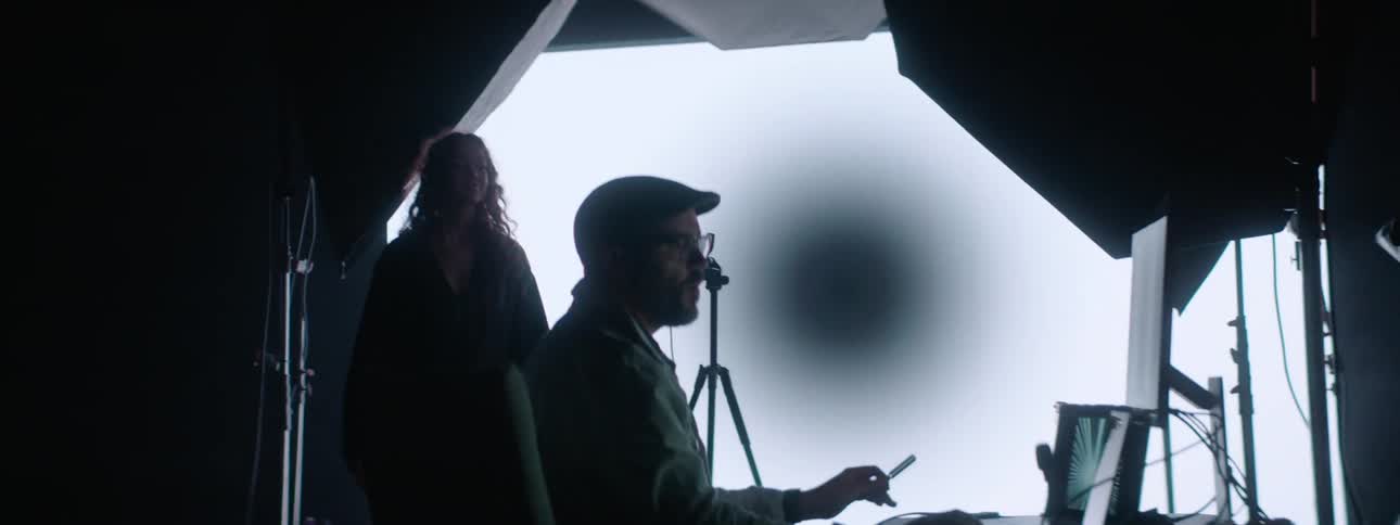 Photographer takes pictures of a model in front of a large projector in the background