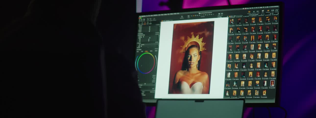 A person sits in front of a computer while editing an image of a woman