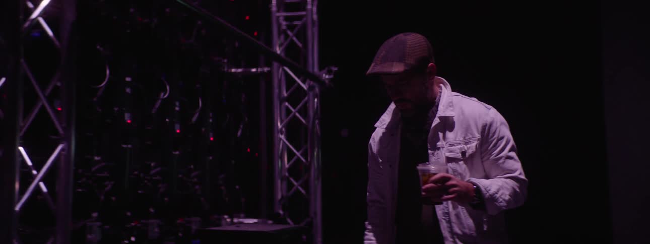 Man carrying a drink walks on the backstage of a studio