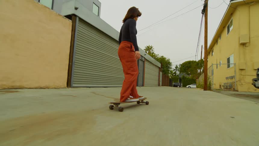 A female skateboarding down an alley