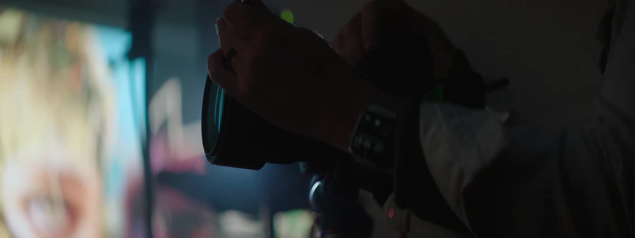 Photographer adjusting the camera on a photoshoot in front of a large projector