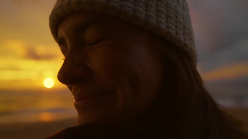 Close up of the face of a happy woman looking at the sunset over the ocean
