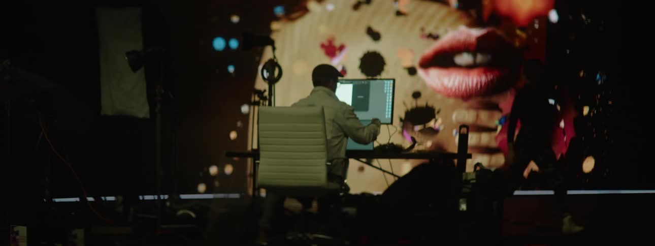 People working on laptops in a photography set with a large projector in the background