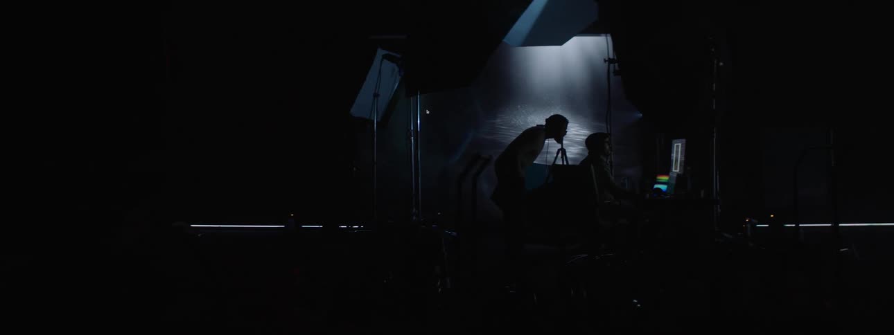 Silhouette of people working on a computer in a photography set with a large projector in the background