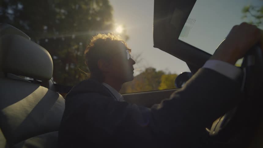 Tired young man wearing sunglasses tries to drive his car