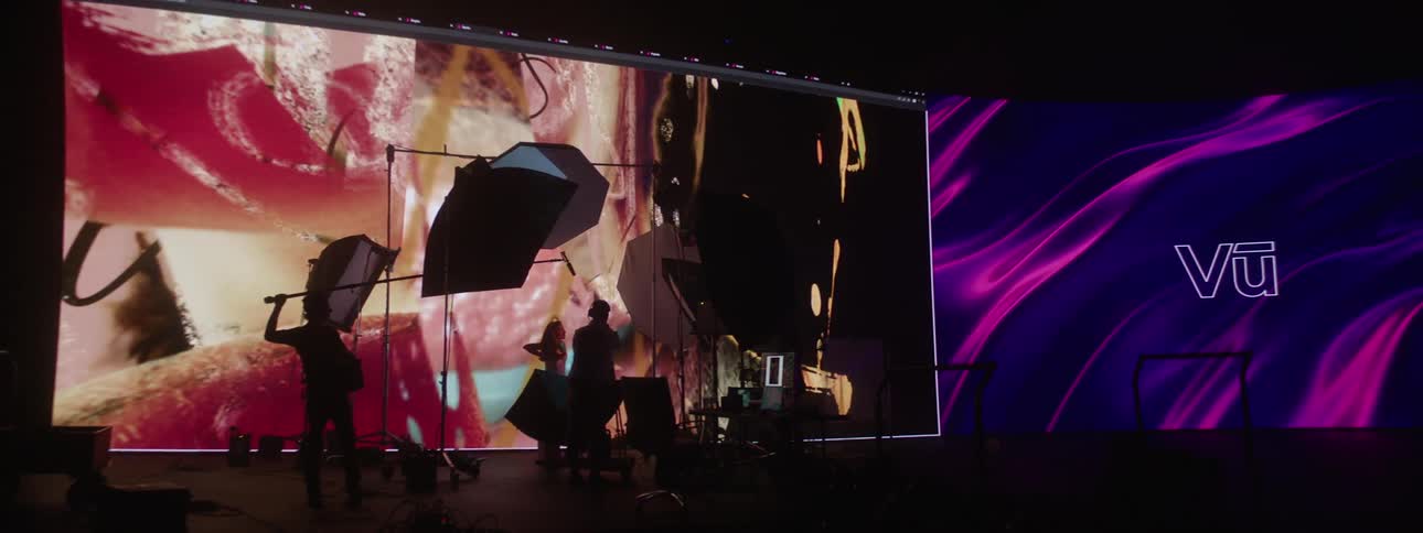 Photography crew helps photographer take pictures of model posing in front of large digital screen
