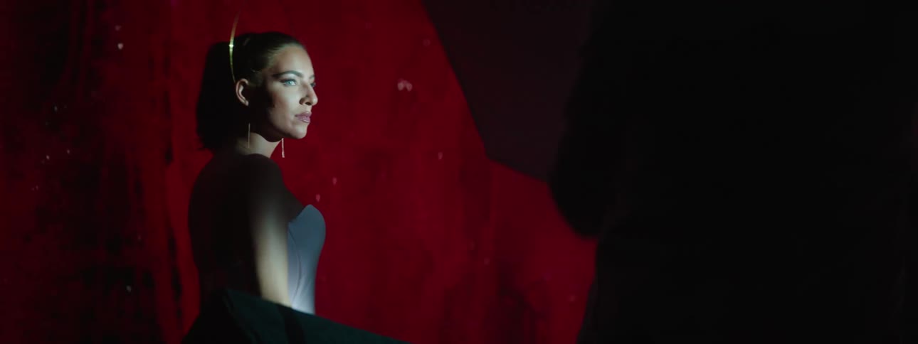 Woman modeling a white dress stands in front of a large projector