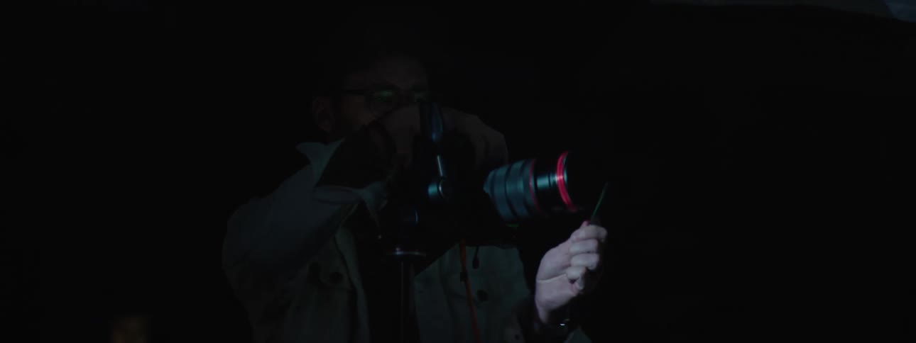 A man talking while placing the right hand on a camera at night