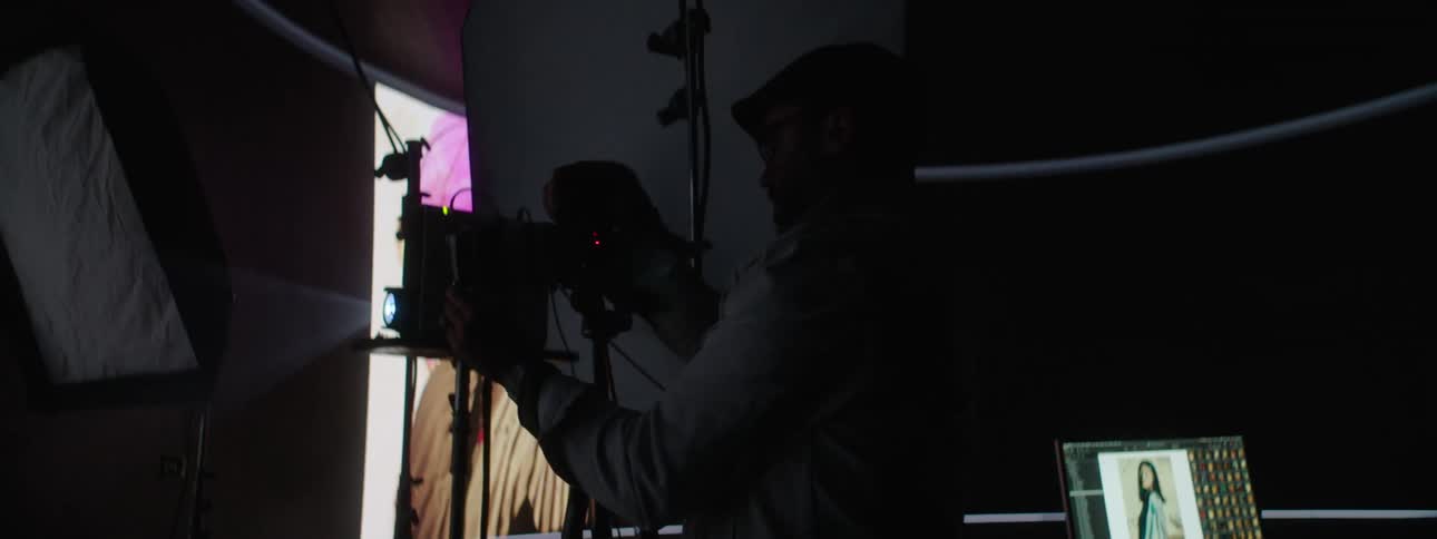 Photographer photographs model posing in photography studio in front of projection screen