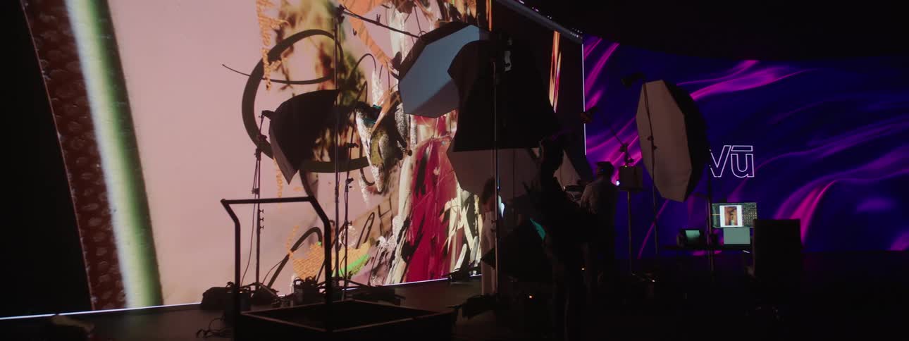 A lady on a stage with a huge screen behind her
