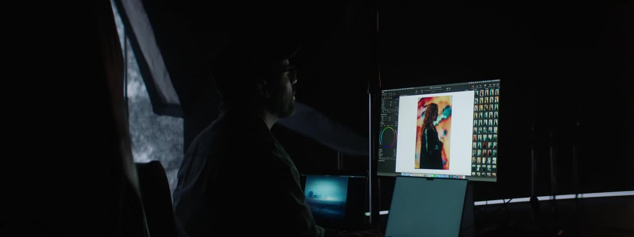 A photographer and a model are watching photos on a computer screen in a photo studio