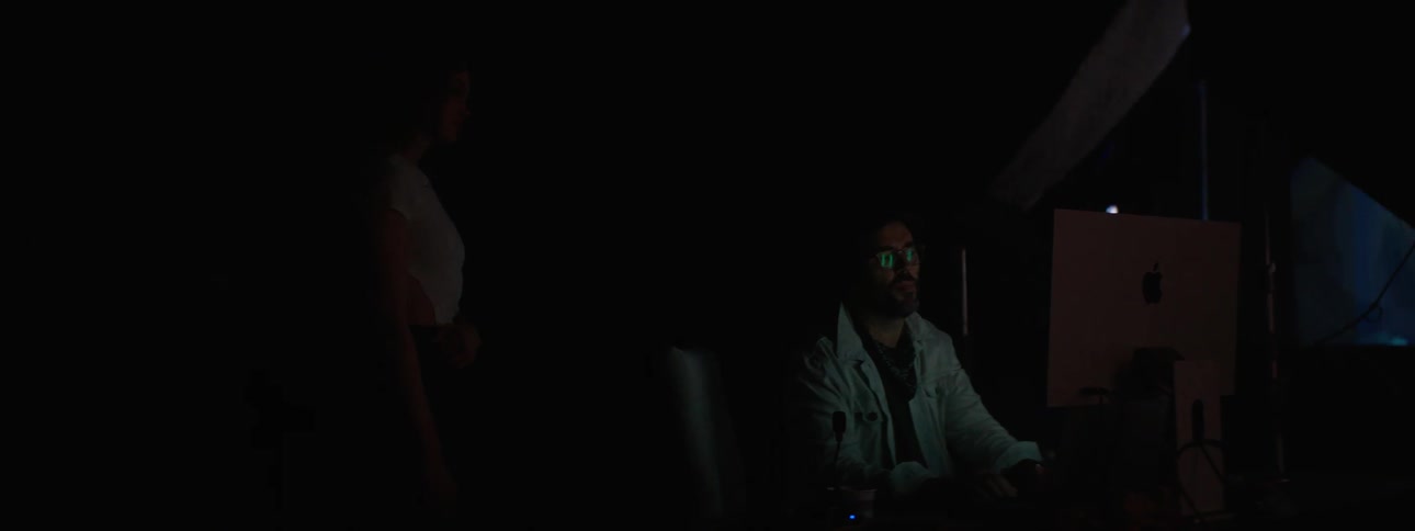 People working on computers in a photography set with a large projector in the background