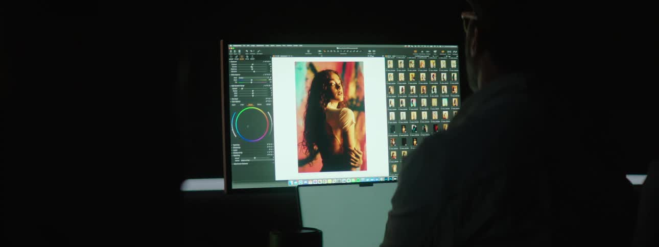 A photographer editing and selecting model shots on a computer in the dark