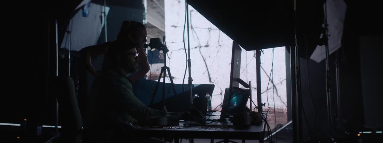 People working on a computer in a photography set with a large projector in the background
