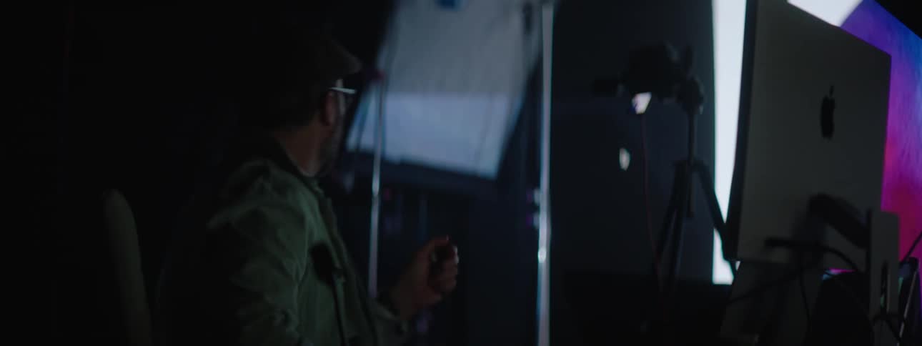 People working on a computer in a photography set with a large projector in the background