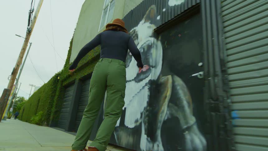 A female skateboarder skateboarding down a sidewalk