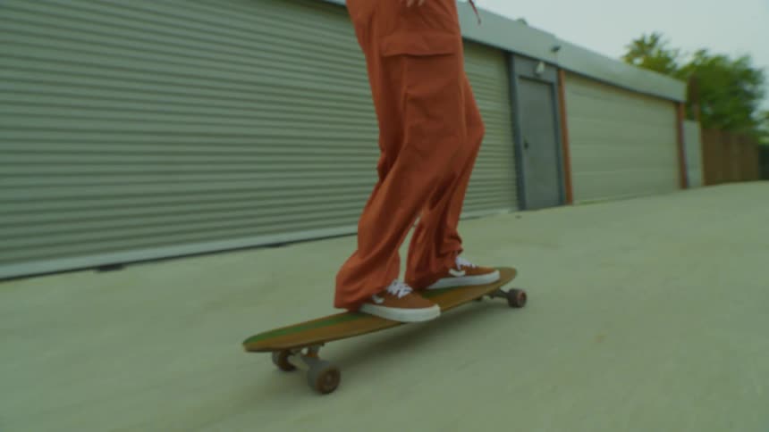 A person riding a longboard down a concrete sidewalk area