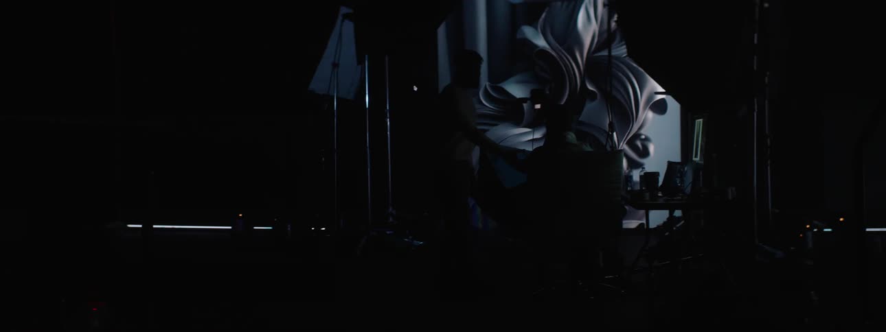 Two people in a dark studio room with visual effects from a laptop projected on a screen