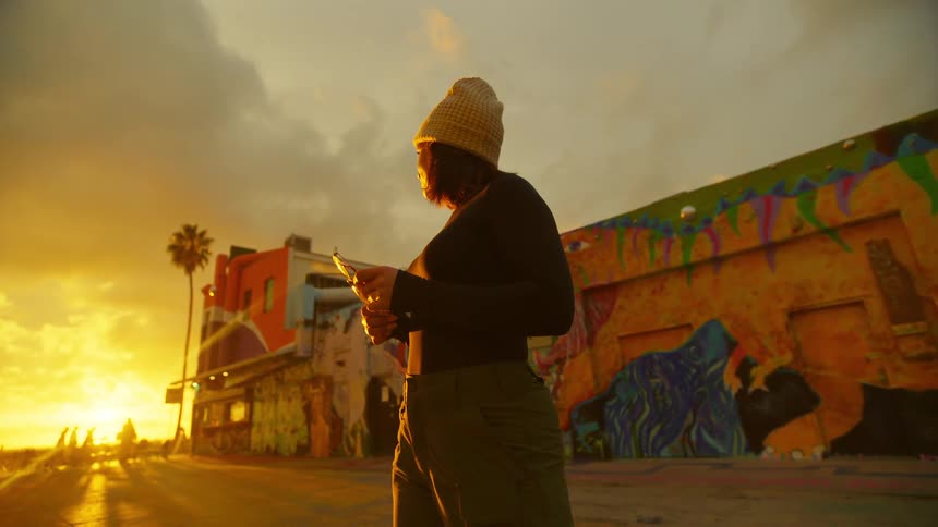 Woman wearing a beanie looking at the bright sunset sun