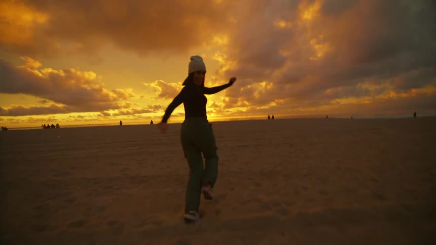 Happy woman running on the beach at sunset