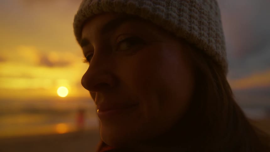 Close up of the face of a happy woman on the beach at sunset