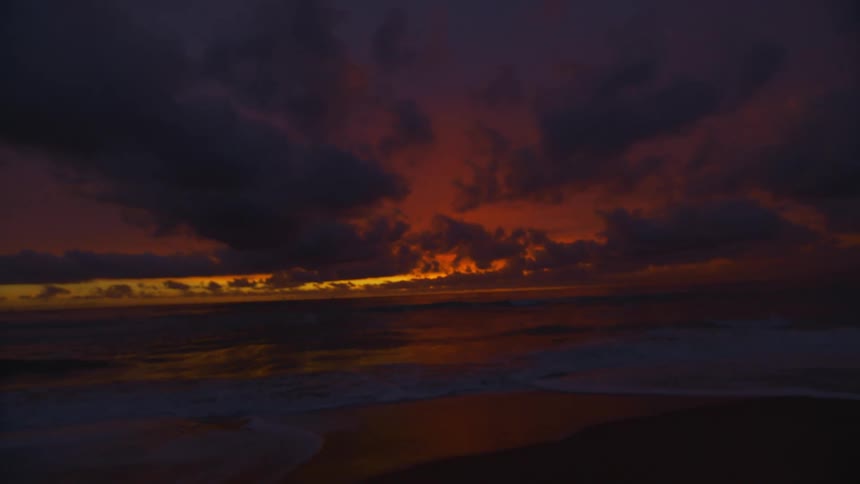 Red sky sunset behind the clouds over the beach