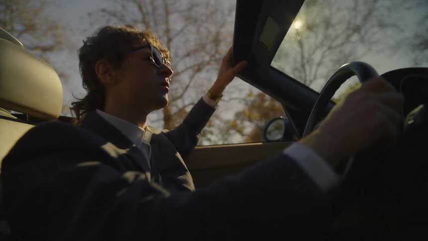 Young man wearing sunglasses driving a convertible car