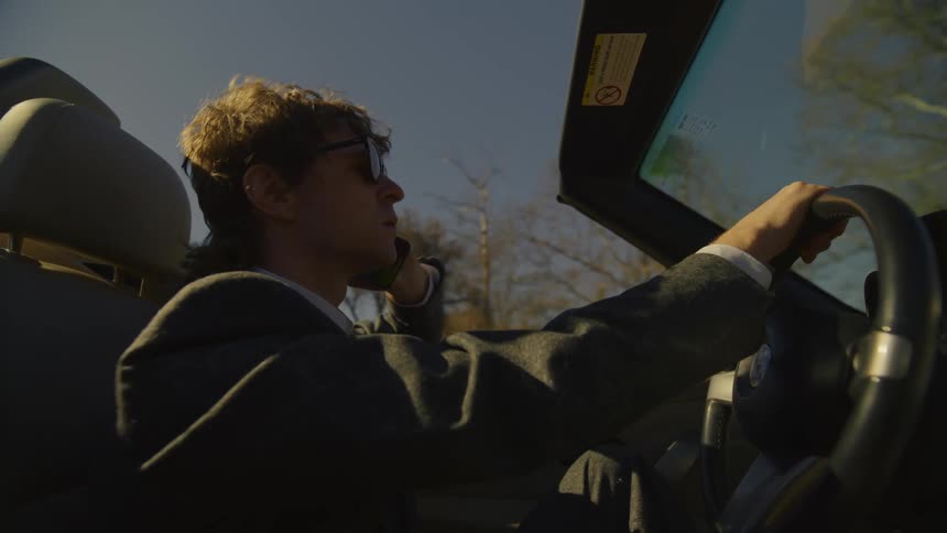 Man wearing sunglasses driving a convertible car