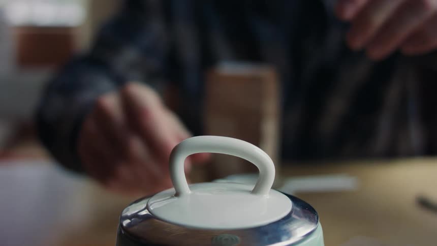 A man sitting at the table takes the lid out of a pot