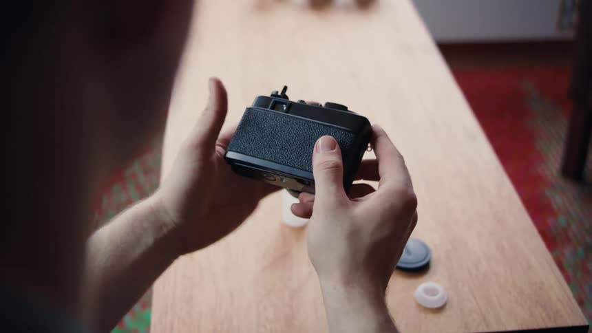 Closeup of a persons hands adjusting the film and closing the lid of a camera