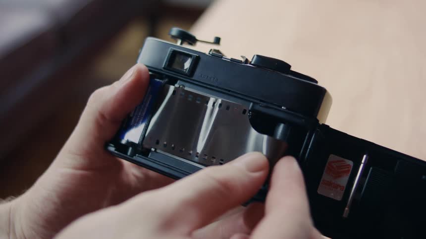 A person inserts a roll of photography film into a small camera