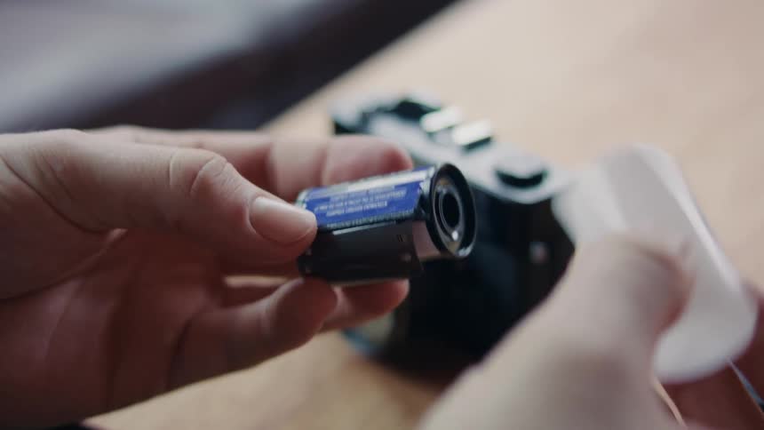 Closeup of a mans hands taking out a vintage camera film from a canister