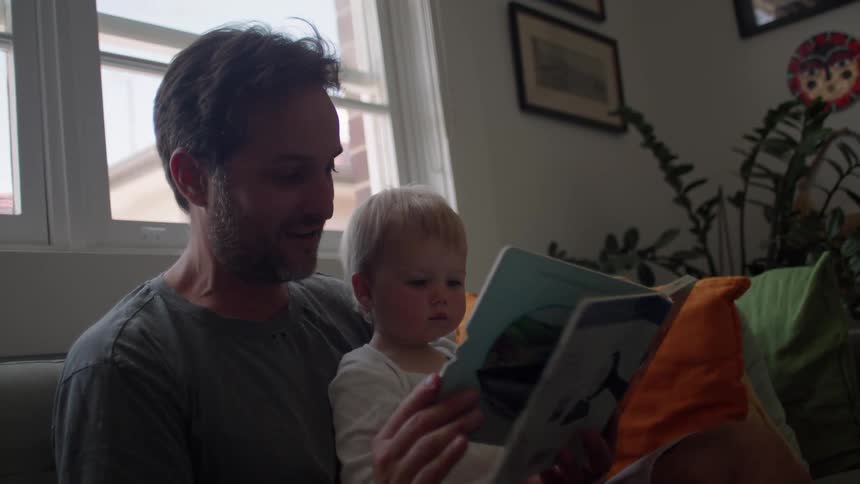 Father holding his baby on his lap and reading a book