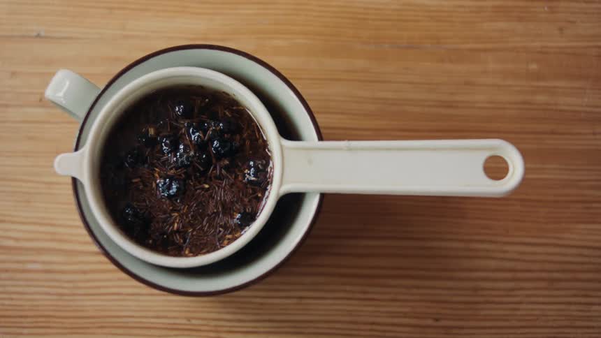 Close up of tea brewing in a colander over a cup