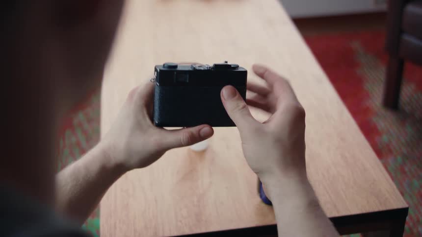Closeup of a mans hands opening a vintage camera and loading the film