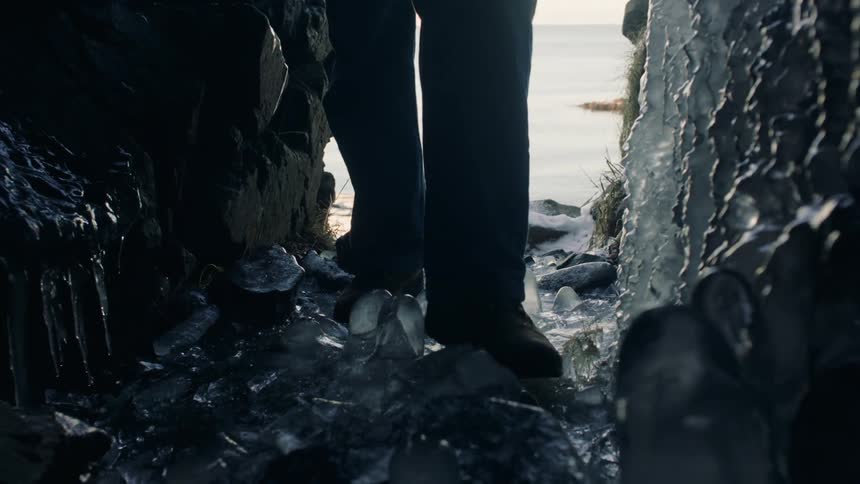 Closeup of a persons legs walking on icecovered natural stones