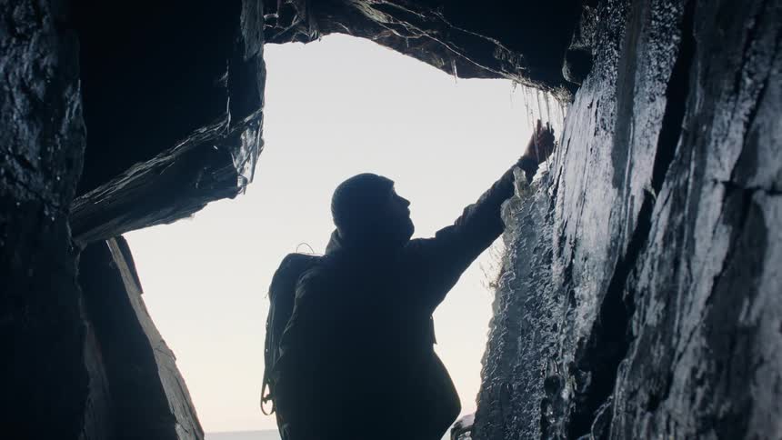 Man in a frozen cave touching the ice