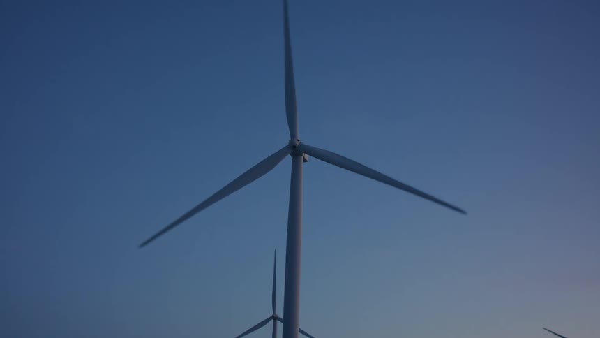 Several towering wind turbines spin slowly to generate electricity